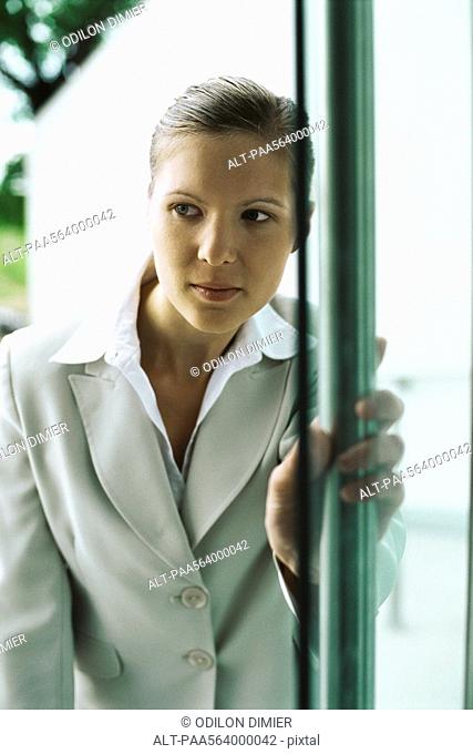 Businesswoman entering building, hesitantly opening door