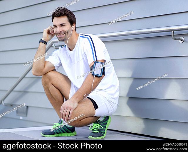 Smiling jogger hearing music with earphones