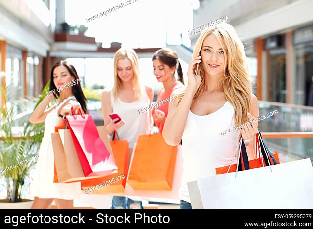 Shopping woman talking on the phone in mall , her friends on background