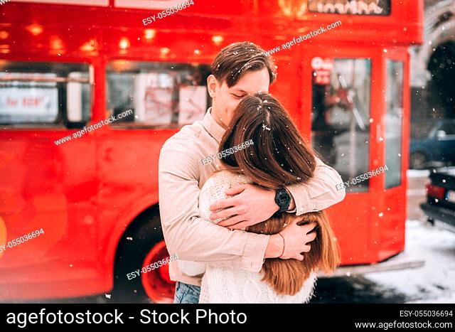 beautiful young couple posing by the old red London bus