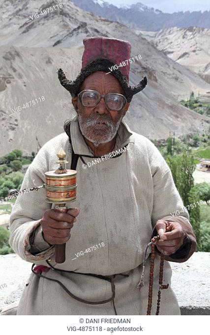 Elderly Ladakhi man with a prayer wheel and prayer beads at the Lamayuru Monastery (Lamayuru Gompa) in Lamayuru, Ladakh, Jammu and Kashmir, India