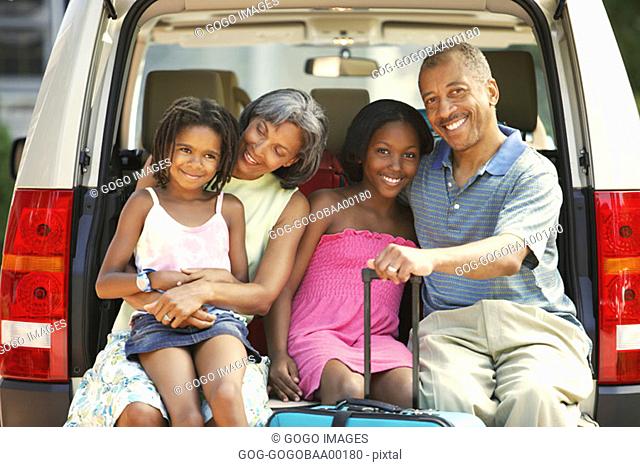 African family smiling in trunk of their SUV