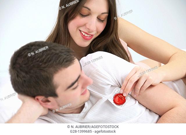 Young couple in bed with red condom