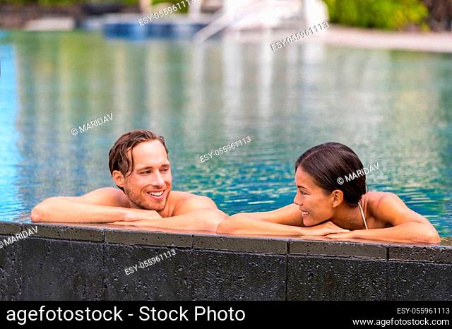 Wellness spa pool couple relaxing in hydrotherapy luxury travel resort on tropical holidays together enjoying the swim in water