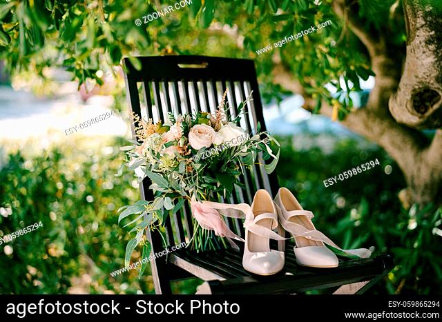 bridal bouquet of white and pink roses, branches of eucalypt tree, astilbe, ammi, small green pomegranates and pink ribbons on the chair