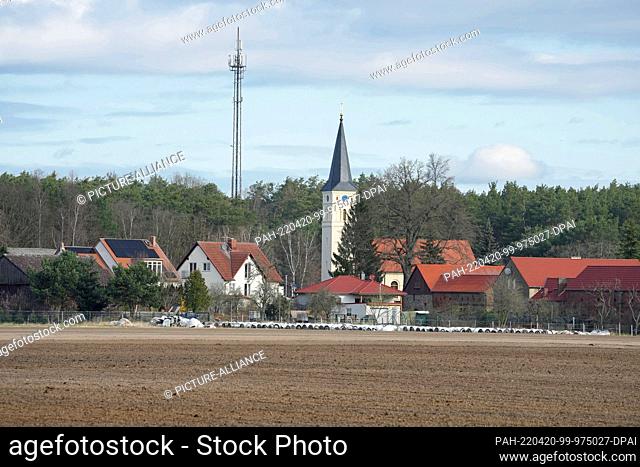 07 April 2022, Brandenburg, Beelitz/Ot Schäpe: The church and dwellings of the village behind an asparagus field. Photo: Soeren Stache/dpa