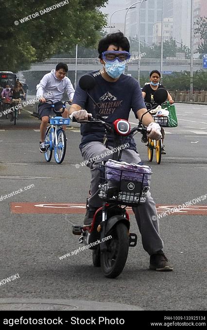 A man wearing face mask, gloves and googles drive scooter in Beijing, China on 18/07/2020 After second outbreak of coronavirus