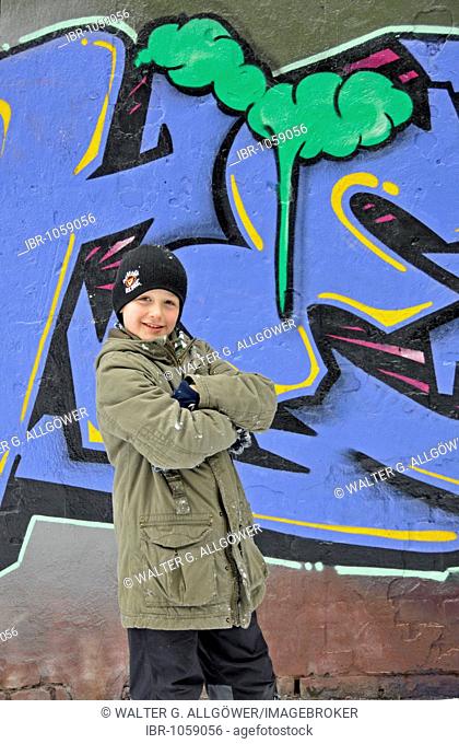 A boy in front of a wall of a football ground sprayed with grafitti, Cologne, North Rhine-Westphalia, Germany, Europe