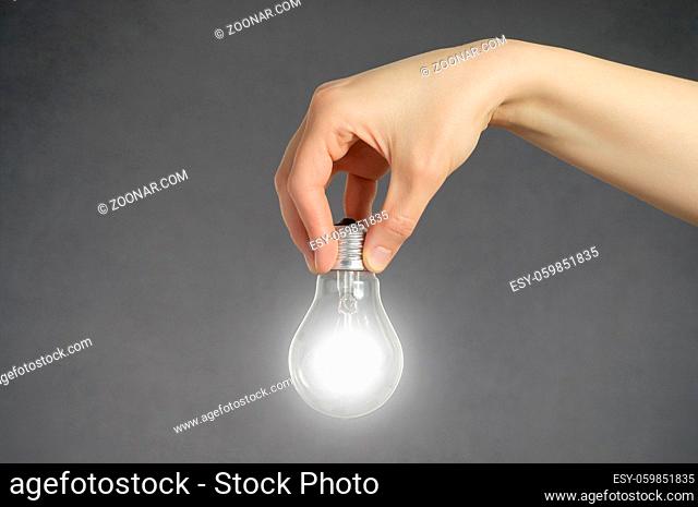 Hand holding a glowing light bulb