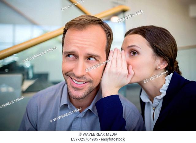-áBusinesswoman whispering something to her colleague