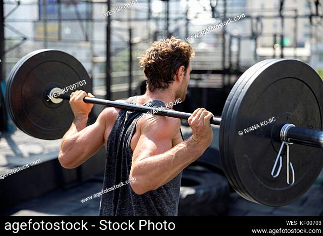 Man lifting barbell exercising at rooftop gym