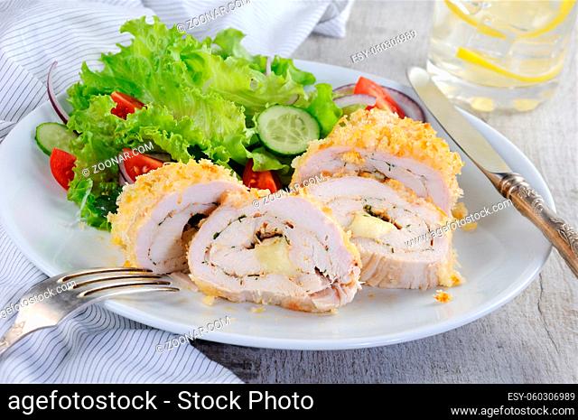 Sliced baked until golden, crispy crust chicken roll in breadcrumbs with Parmesan cheese, stuffed with cheese with herbs and garnish of vegetables