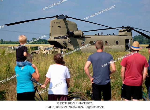 05 June 2018, Germany, Delitzsch: Onlookers watching loading work on a US Armed Forces helicopter in a field near to the town of Beerendorf near Delitzsch
