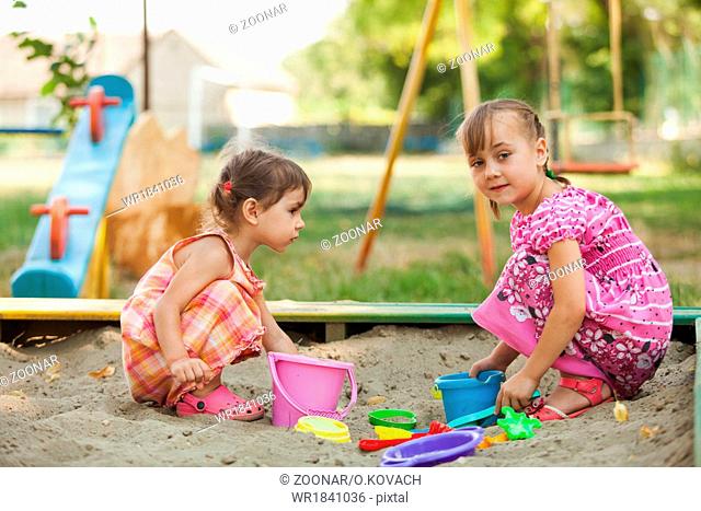 Two girls play in the sandbox