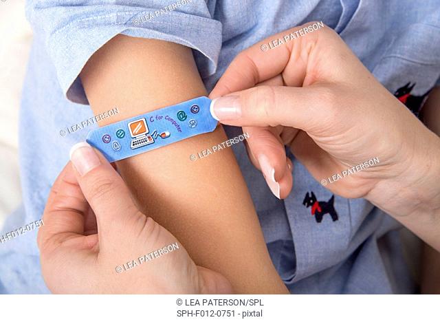 Person applying plaster to girl's arm