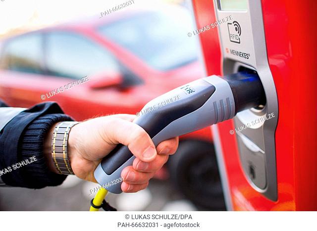 A police officer inserts a plug into a charging pole for electric cars in Hamburg, Germany, 09 March 2016. The city of Hamburg has set up a new charging pole...