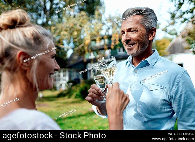 Smiling couple toasting champagne flute at backyard
