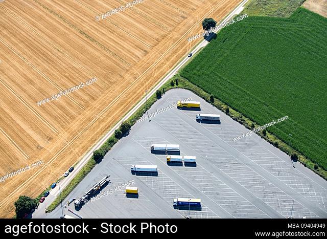 Ludtaufnahme of a truck parking lot on the edge of large agricultural fields