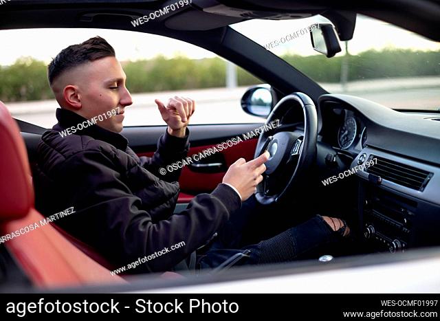 Young man using mobile phone while sitting in car