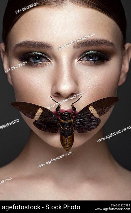 Portrait of beautiful girl with colorful make-up and cicada. Beauty face. Photo taken in the studio