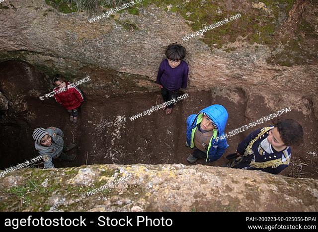23 February 2020, Syria, Idlib: Syrian children pictured oustide a cave at Taltouna village. At least eight families live in an ancient deserted cave after...