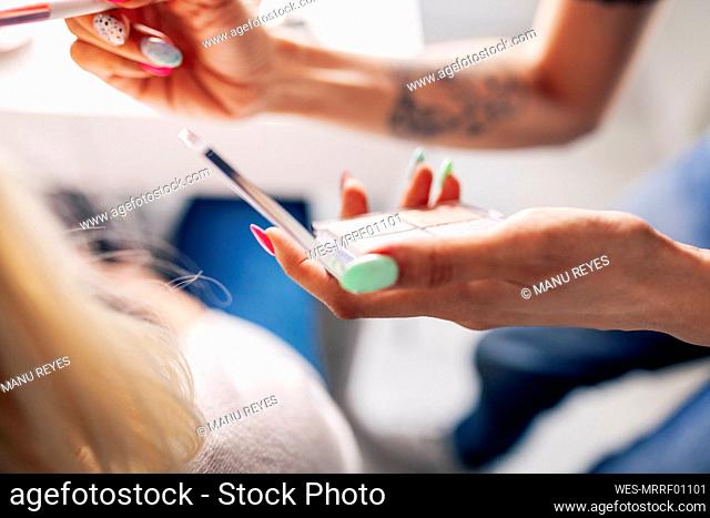 Female make-up artist applying highlighter to model in studio