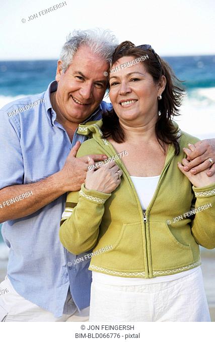 Hispanic couple hugging on beach