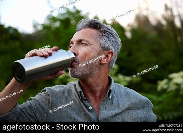 Male hiker drinking water from bottle in forest