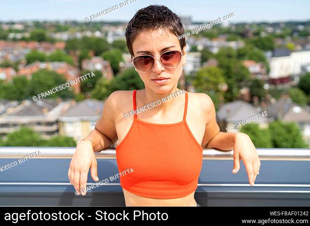 Portrait of woman on roof terrace wearing orange top and sunglasses