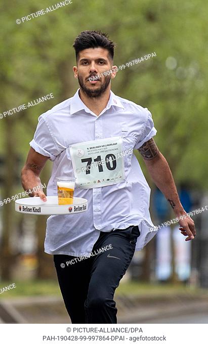 28 April 2019, Berlin: With a filled tray, a waiter walks across the Kurfürstendamm at the 9th Berlin Waiter Run. Waiters, barkeepers