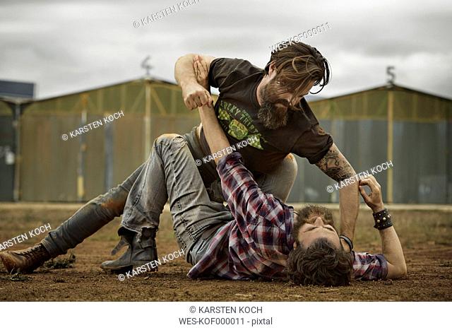Two men with full beards fighting in abandoned landscape
