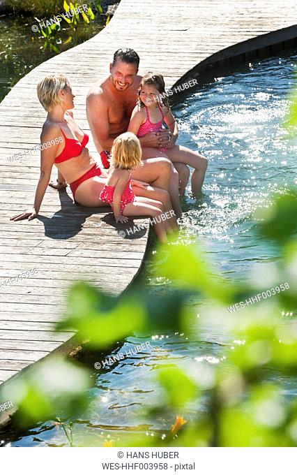 Austria, Salzburg County, Family sitting on bridge over pond