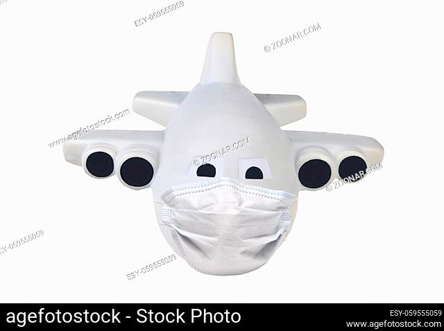 Covid-19 and travel restrictions concept. Toy Airplane with a surgical mask isolated on whte
