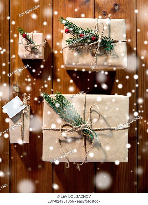christmas, holidays, presents, new year and decor concept - close up of gift boxes wrapped into brown mail paper and decorated with fir brunch and rope bow