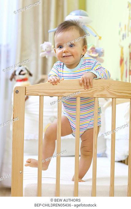 Child sitting in baby cot