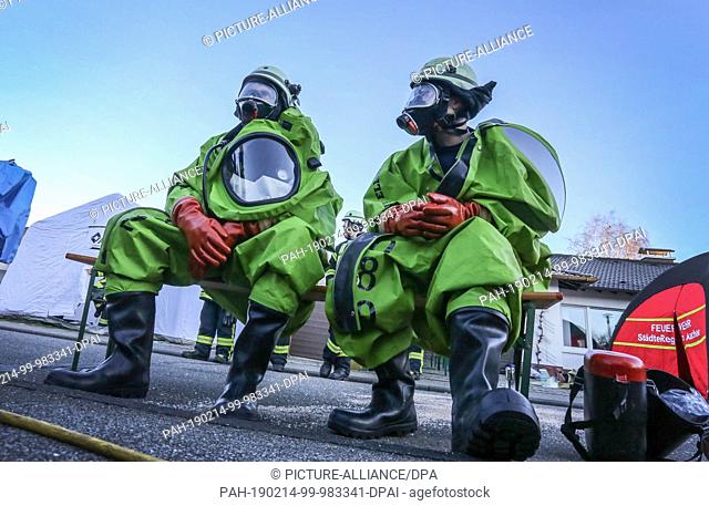 14 February 2019, North Rhine-Westphalia, Alsdorf: Firefighters dressed in protective suits sit in front of a house. Long stored and obviously forgotten...