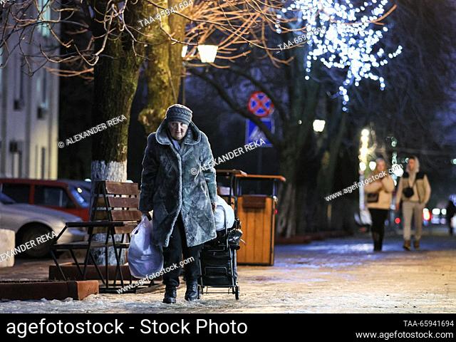 RUSSIA, LUGANSK - 20 de diciembre de 2023: Una mujer pasea mientras las luces de cuerda cuelgan de los árboles en la Plaza de los Héroes de Guerra