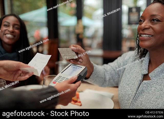 Female customer paying waitress with smart card at cafe