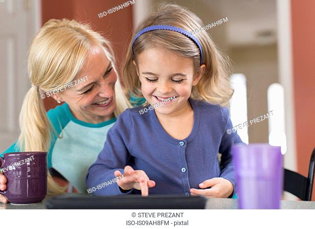 Mother and young daughter with digital tablet