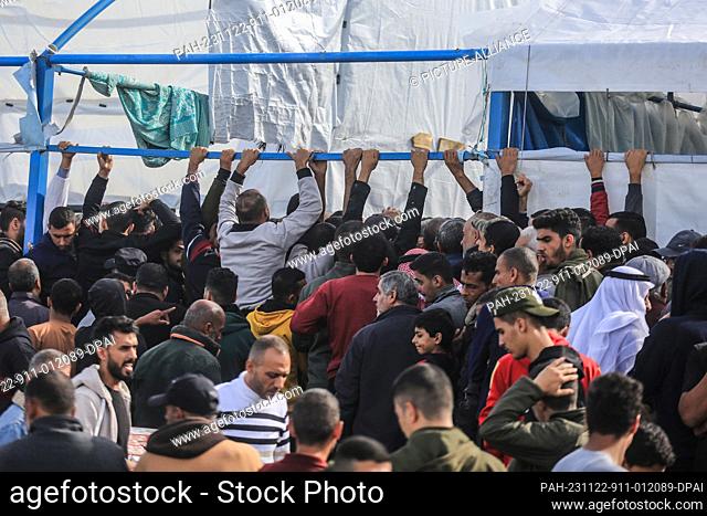 22 November 2023, Palestinian Territories, Khan Yunis: Palestinians wait to receive bags of flour at the United Nations Relief and Works Agency for Palestinian...