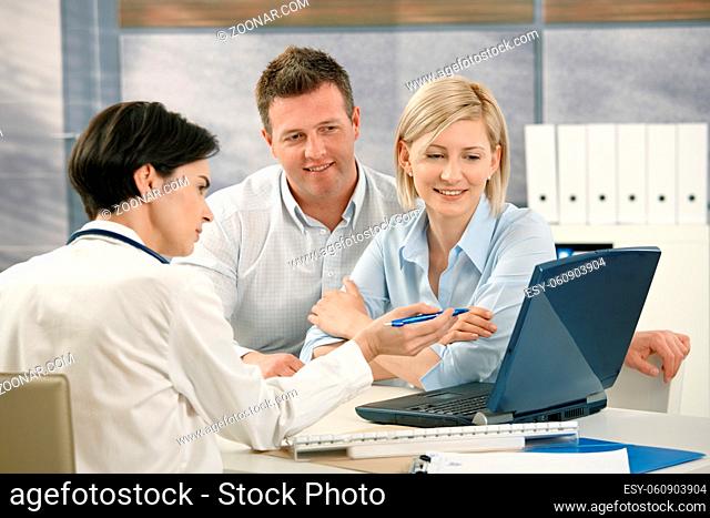Medical doctor showing results to patients on computer in office