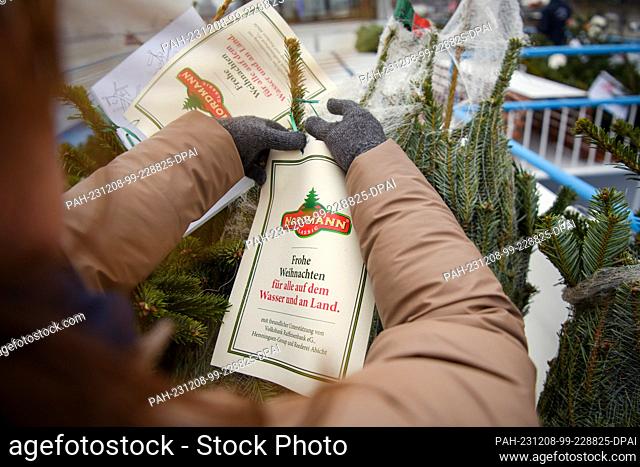 08 December 2023, Hamburg: A leaflet (""Merry Christmas for everyone on the water and on land"") is hung on a Christmas tree during the ""Christmas trees for...