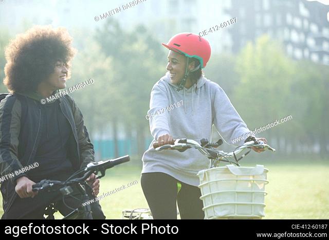 Happy twin brother and sister riding bicycles in park
