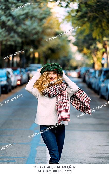 Portrait of happy young woman wearing Christmas wreath on her head dancing on the street