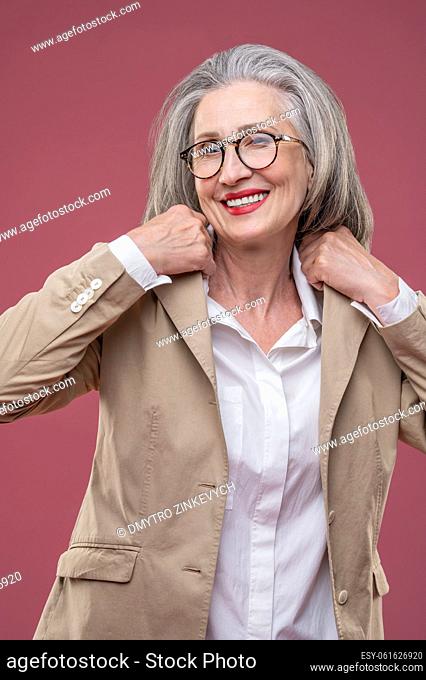 Looking good. Woman in light jacket standing and looking confident