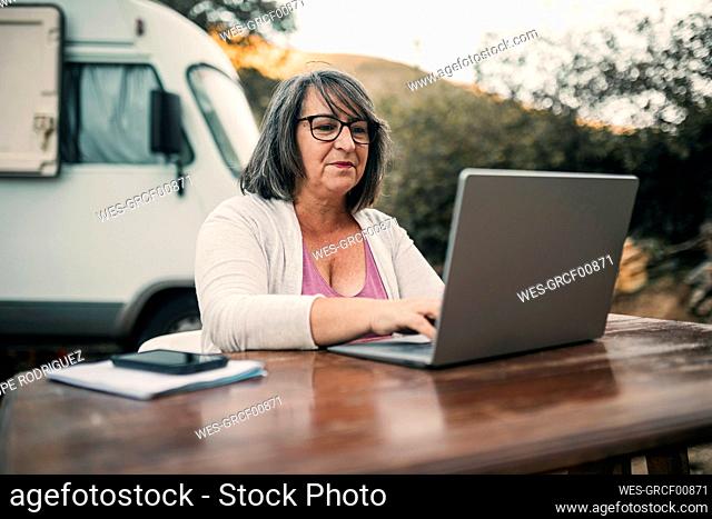Woman wearing eyeglasses using laptop at table