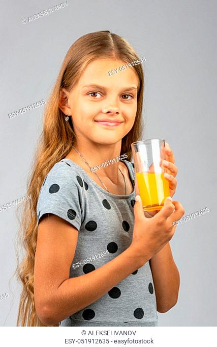 The girl proudly holds a glass of juice
