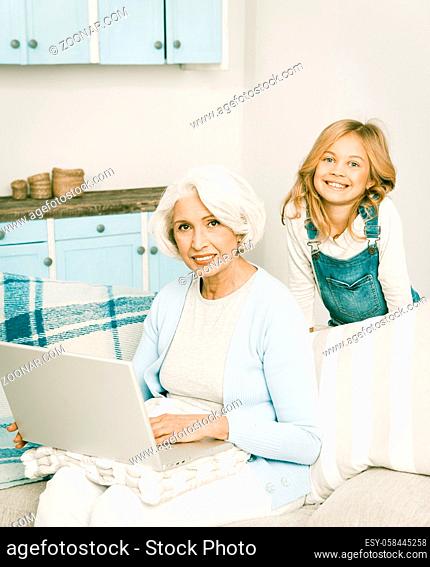 Adorable Granddaughter Teaching Her Grandmother How To Play On Computer Happy Granny Using Laptop Computer Cheerful Ladies Smiling For Camera, Toned Image