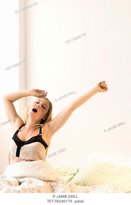 Young woman stretching in bed