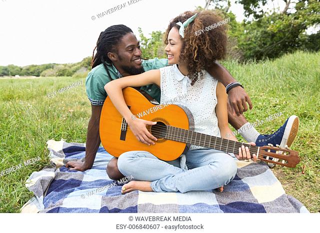 Young couple on a picnic playing guitar